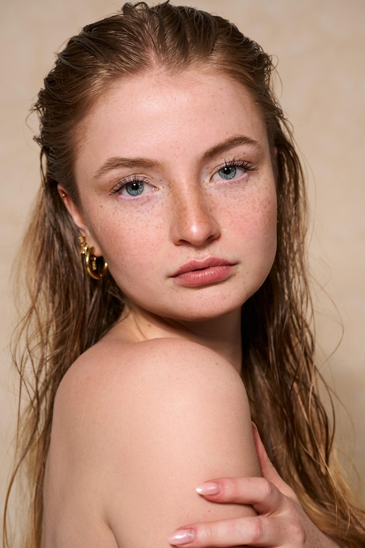Studio portrait of Zoe Schmidt with wet hair, looking over her shoulder.